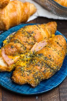 a blue plate topped with chicken covered in cheese and seasoning next to a croissant