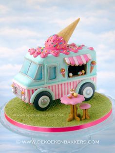 an ice cream truck is decorated with pink and blue icing, while the cake has a large cone on top