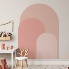 a living room with pink and white decor on the wall, two stools and a small table