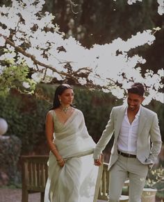 a man and woman holding hands in front of a tree