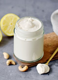 a glass jar filled with whipped cream next to sliced lemons and cashews