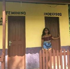 a woman standing in the doorway of a yellow building with two doors on each side