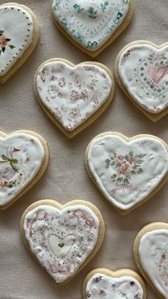 several decorated heart shaped cookies sitting on top of a cloth covered table next to each other