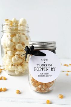 a jar filled with popcorn sitting on top of a white table next to another jar