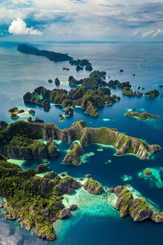 an aerial view of several small islands in the ocean with blue water and green vegetation