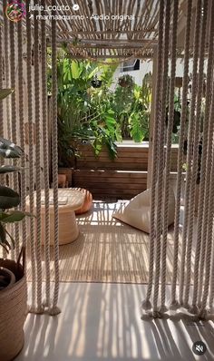 the inside of a house with plants and hanging curtains on the outside wall, as well as potted plants