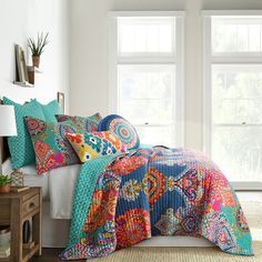 a bed with colorful comforters and pillows in a room