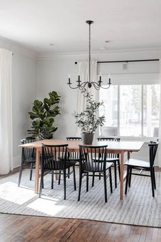 a dining room table with black chairs and a potted plant on top of it