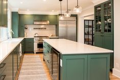 a large kitchen with green cabinets and white counter tops, along with an area rug on the floor