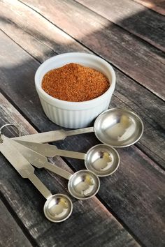 measuring spoons and measuring cups with spices in them on a wooden table top next to measuring spoons