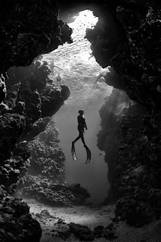 a person swimming in the water through a cave