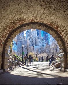 people are walking under an arch in the city