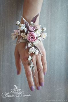 a woman's hand holding a pink and white wrist corsage with flowers on it