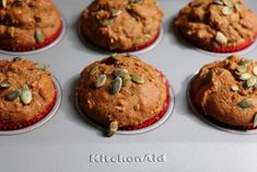 six muffins with pumpkin seeds on top in a cupcake tin