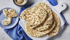 flatbreads and butter on a white plate with blue cloth next to it,