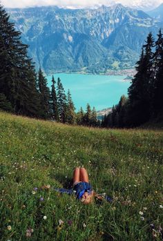 a person laying in the grass on top of a hill