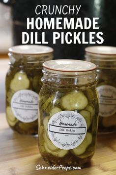 three jars filled with pickles sitting on top of a wooden table