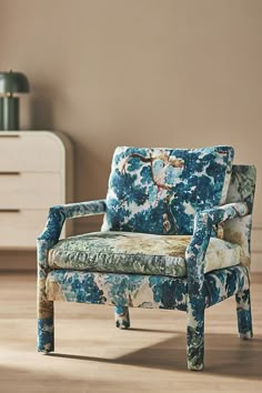 a blue chair sitting on top of a hard wood floor next to a white dresser