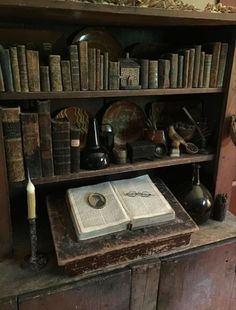 an old wooden book shelf filled with books and other antique items on top of it