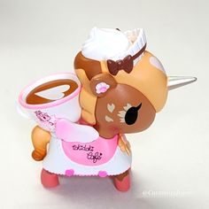 a toy doll holding a cup of coffee with whipped cream on it's head