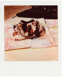 a brown and white hat sitting on top of a table next to a map with a black car in the background