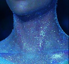 a woman's face covered in blue and white glitter