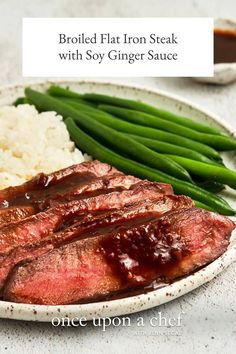 broiled flat iron steak with soy ginger sauce on a plate next to rice and green beans