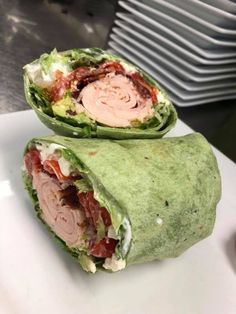 two wraps with meat, lettuce and tomato on them sitting on a plate