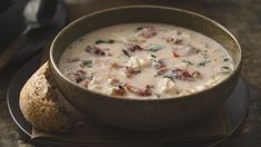 a bowl of soup sitting on top of a plate next to a piece of bread