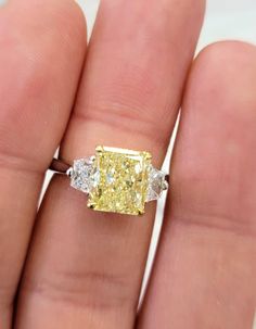 Classic and beautiful three stone ring with a 3ct Fancy Yellow elongated Radiant cut set in Platinum and 18kt Yellow Gold with 0.50ct total weight colorless trapezoids Princess Cut Three Stone Ring, Elongated Radiant Cut, Elongated Radiant, Expensive Purses, Yellow Diamonds Engagement, Curated Wedding, Yellow Diamond Rings, Three Stone Ring, Wedding Dreams