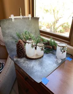 three mason jars with pine cones are sitting on a table