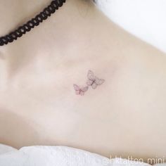 a woman's chest with two small butterflies on her left side, and the upper part of her breast visible