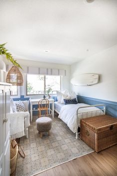 a bedroom with two beds and a table in the corner next to a window that has a surfboard on it