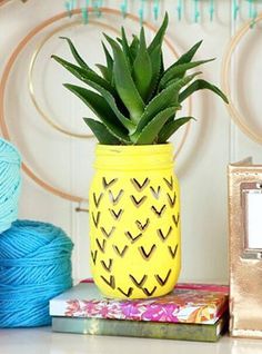 a pineapple potted plant sitting on top of a table next to some yarn