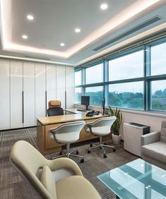 an office with two desks and chairs in front of large windows overlooking the city