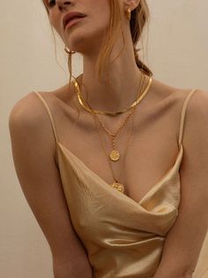 a woman wearing a gold dress and necklace