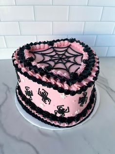 a pink and black spider web cake on a white plate with marble countertop in the background