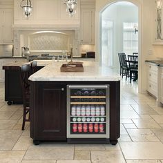 a large kitchen with an island in the middle and wine cooler on the other side