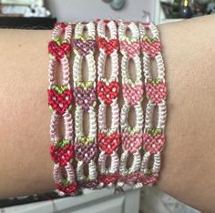 a close up of a person's arm wearing a bracelet with hearts on it