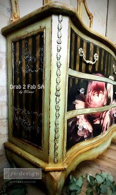 an old dresser with flowers painted on the front and side panels, sitting on a wooden floor