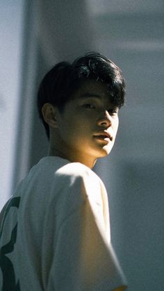 a young man standing in front of a building with his head turned to the side