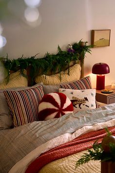 a bed with red and white pillows on top of it next to a night stand