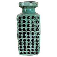 a green vase with black dots on it