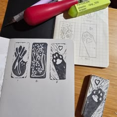 a notebook with some drawings on it next to a pen and eraser that is sitting on top of a table