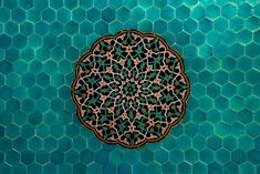 an intricate design on the side of a green tiled wall with hexagonal tiles