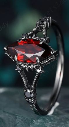 a ring with a red stone in the center and silver accents on it's sides