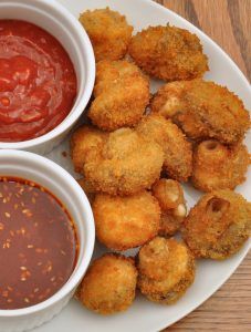 two bowls of dipping sauce next to some fried food on a plate with tater tots and ketchup