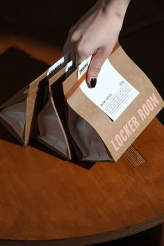 a person is holding some brown paper bags on a wooden table and reaching for it