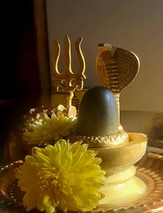 a golden plate topped with yellow flowers next to a metal object on top of a table