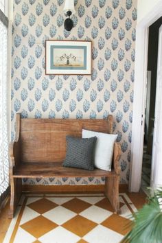 a wooden bench sitting in the middle of a room next to a door and window